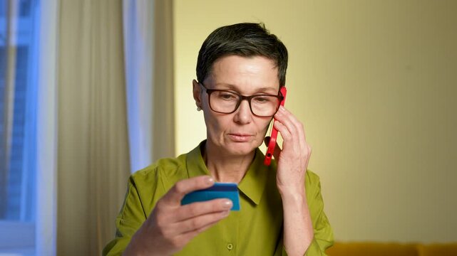 Phone scammers misleading senior woman to share personal identity data and bank credit card number information. Manipulative thefts talking with lady on smartphone and receiving financial details.