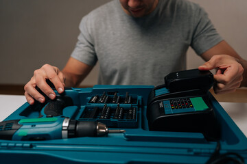 Cropped shot of worker preparing tools, charging power drill battery for upcoming diy project, demonstrating home improvement and maintenance skills with power equipment.