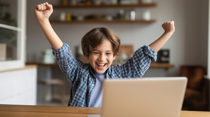 A happy child raises fists in celebration while sitting at a laptop during a successful learning moment at home.
