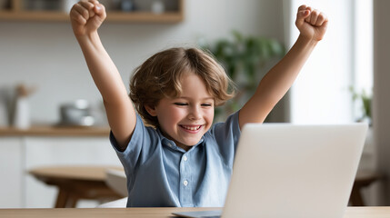 A happy child raises fists in celebration while sitting at a laptop during a successful learning moment at home.
