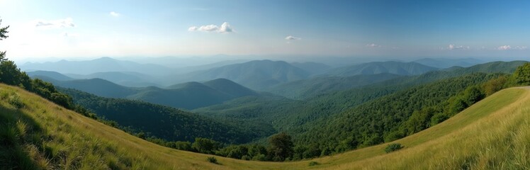 Obraz premium Panoramic view of rolling green mountains under a blue sky. Hazy layers of Appalachian ridges stretch to the horizon from a grassy overlook on the Blue Ridge Parkway.