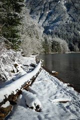 Chilliwack lake beach covered in fresh snow on sunny winter day 