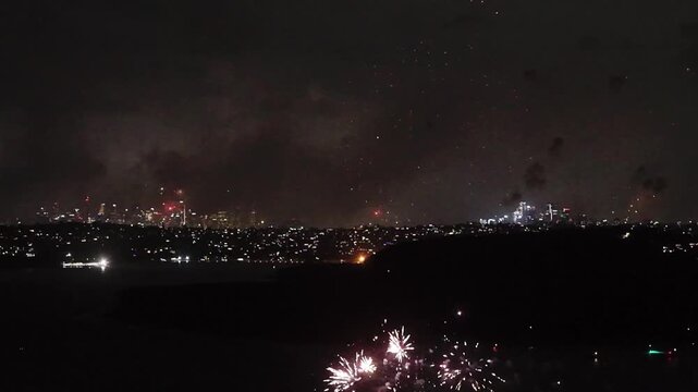 Manly cove New Year Eve fireworks over Sydney Harbour and distant CBD show.