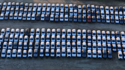 Rows of new cars in a large outdoor parking lot viewed from an aerial perspective, representing automotive industry production, distribution, logistics, shipping, and storage