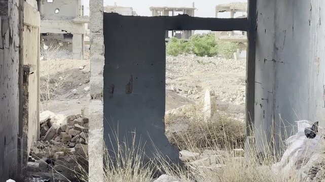 A ruined building's doorway shows a scene of devastation and decay after conflict.