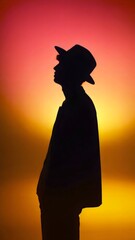 Silhouette of man in hat against vibrant sunset background