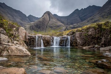 Scenic waterfall flows into a calm pool against mountain backdrop