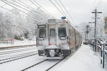 Train departing from Overbrook train station during a snowstorm