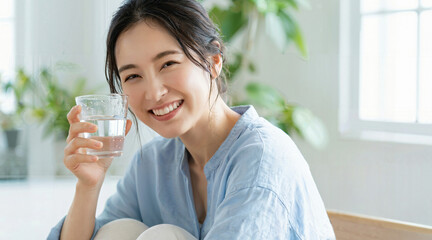 Young Japanese woman drinking a glass of water, healthy lifestyle and skincare concept