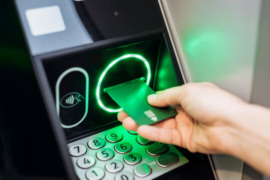 Hand inserting a contactless payment card into an ATM machine, illuminated keypad and screen displaying transaction options, showcasing modern banking technology and convenience - Powered by Adobe