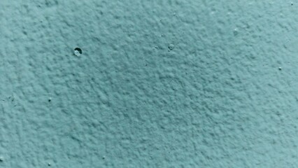 Detailed shot of a textured teal surface highlighting small craters, pockmarks, and irregular paint application patterns.