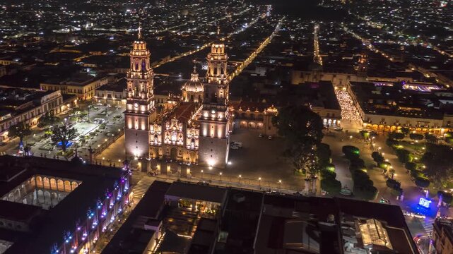 Nighttime hyperlapse orbiting the illuminated Catedral de Morelia, highlighting its baroque towers and the glowing historic center under city lights.
