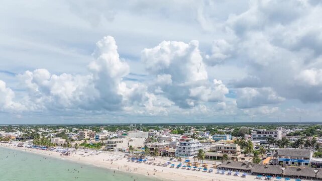 Aerial hyperlapse over Progreso&rsquo;s coastline, revealing a crowded beach, turquoise waters, and dramatic cloud formations as the city stretches along the Yucat&aacute;n shoreline