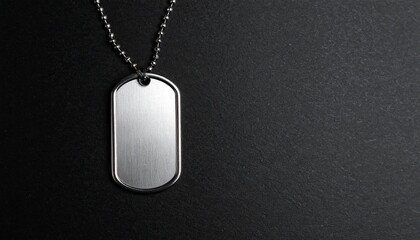 A single metallic dog tag hangs from a silver chain against a stark black background