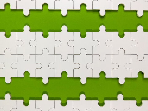 Clean, minimalist image of white jigsaw puzzle pieces arranged in rows against a bright green background, representing connectivity, strategy, business logic, and creative problem-solving.