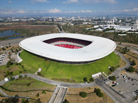 Zapopan, Mexico - December 7: Aerial drone view of modern Akron Stadium in Guadalajara, showing its distinctive white roof, red seats, green landscape, and urban areas