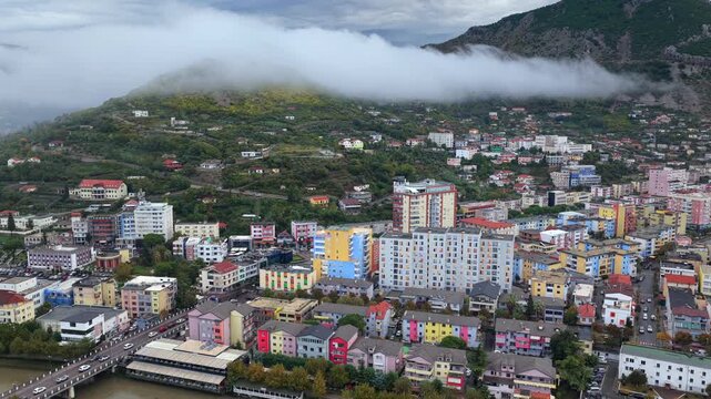 Aerial video of Lezh&euml;, Albania with fog sliding over the hillside rising above colourful city blocks.