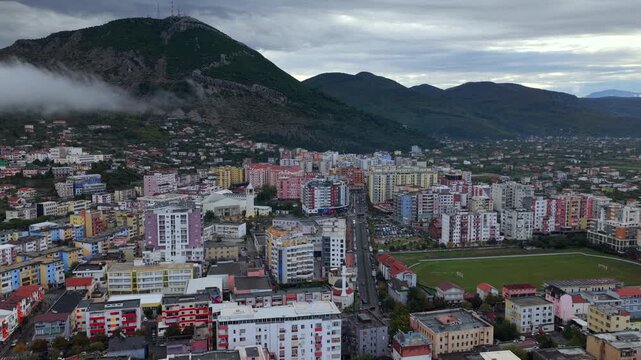 Aerial  video of Lezh&euml; with fog sliding over the hillside and Skanderbeg&rsquo;s Tomb Peak rising above colourful city blocks.