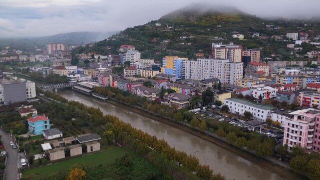 Aerial video of Lezh&euml;, Albania with fog sliding over the hillside rising above colourful city blocks.