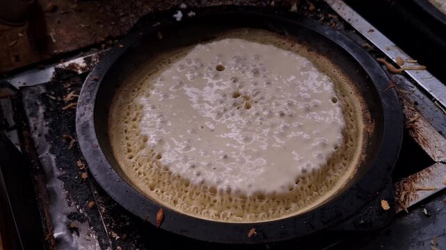 Batter of mini sweet martabak or pancake sizzling in a pan of a street vendor