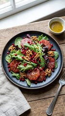 salad features orange slices pomegranate seeds walnuts and mixed greens served on a dark plate