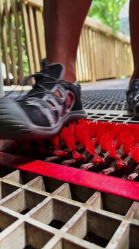Hiker cleaning hiking shoes on a foot brush station