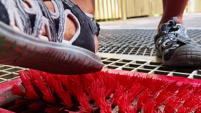 Hiker cleaning hiking boots on a red shoe brush