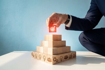 Businessman hand placing red target block on wooden pyramid to achieve business strategy goals