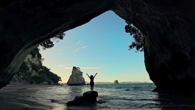 Silhouette of a woman celebrating at Cathedral Cove beach