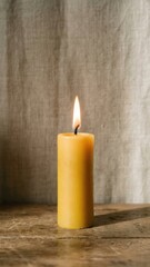 single lit yellow candle with glowing flame and blackened wick on neutral background evoking calm mood