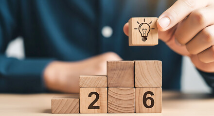 Hand placing wooden block with lightbulb symbol on stacked blocks showing numbers cube
