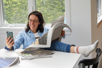 Working mom having a moment to herself to enjoy her newspaper and her cell phone on a weekend morning