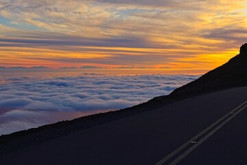 The sun sets above the clouds at the summit of the Haleakala volcano on Maui