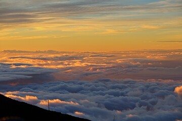 The sun sets above the clouds at the summit of the Haleakala volcano on Maui