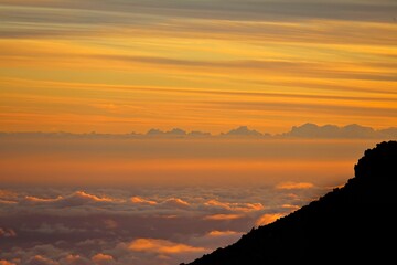 The sun sets above the clouds at the summit of the Haleakala volcano on Maui