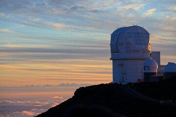 The sun sets above the clouds at the summit of the Haleakala volcano on Maui