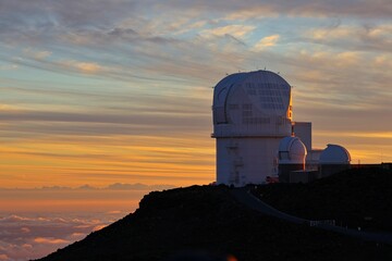 The sun sets above the clouds at the summit of the Haleakala volcano on Maui