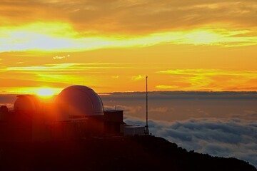 The sun sets above the clouds at the summit of the Haleakala volcano on Maui