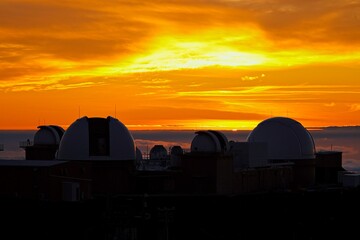 The sun sets above the clouds at the summit of the Haleakala volcano on Maui