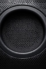close-up of a textured circular speaker cone within a perforated metal grill, moody dramatic lighting conveying power and intensity