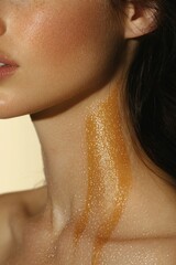 Close-up of female neck, ear and collarbone with honey-like golden liquid and shimmering glitter, sensual and glamorous mood