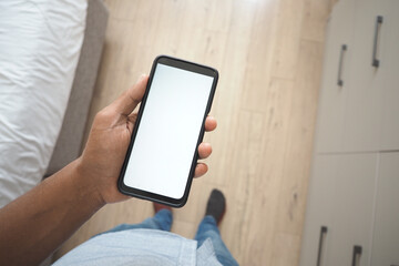 Person holds smartphone above floor in home setting