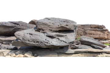 A rough stack of natural brown stones creates a textured mineral wall against a blue sky and mountain landscape