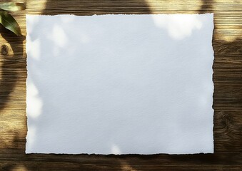 Blank textured white sheet with torn edges on rustic wooden table, dappled sunlight and leaf shadows creating a calm natural creative atmosphere