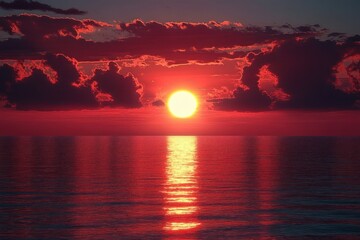 Glowing red sunset over calm ocean with a bright sun, dramatic dark clouds and a golden reflection on rippling water, peaceful and awe-inspiring