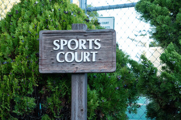 Rustic wooden sign indicating 'Sports Court' surrounded by lush green foliage
