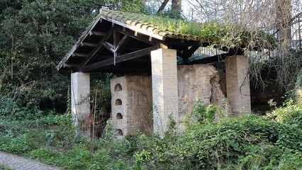Rome, Italy &ndash; 14 January 2025. A Roman-era columbarium with arched niches is sheltered under a modern roof on the Via Appia, nestled among thick greenery and overgrowth.