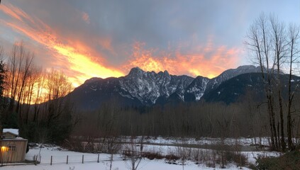 A breathtaking winter sunset paints the snow-capped mountain peaks in vibrant hues of orange and pink.