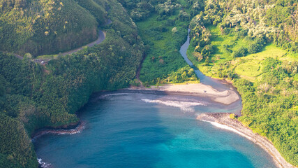 Aerial view of coastal blue cove and beach with river landscape along road to Hana in Maui, Hawaii with green hills and ocean seascape
