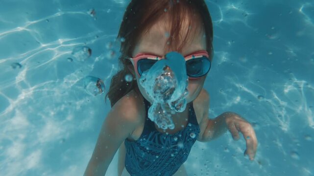 Girl swims underwater in the pool. Pre teen girl feels herself comfortable and relaxed underwater. Little girl dives and swims in the pool